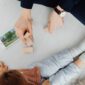 Seorang anak balita sedang asyik merangkai mainan balok kayu bersama orang tuanya di ruang keluarga yang hangat. Aktivitas fisik sederhana ini terbukti ampuh menstimulasi saraf motorik halus dan mempererat hubungan emosional keluarga.