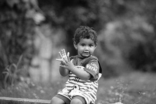 Seorang anak kecil sedang asyik bereksplorasi di taman terbuka sambil menyentuh dedaunan dan rumput basah. Aktivitas alami di luar ruangan ini sangat berguna untuk melatih kecerdasan motorik serta sensorik anak.