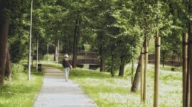 Seorang pekerja perkotaan menikmati udara segar sembari berjalan kaki santai di taman kota untuk menjaga kebugaran tubuh di sela kesibukan harian.