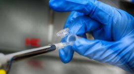 Seorang peneliti medis sedang mengamati sampel rekayasa seluler di laboratorium steril berpenerangan khusus untuk pengembangan terapi gen terapan.