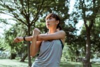 Seorang wanita menikmati kesegaran udara pagi sambil melakukan peregangan ringan di taman kota untuk menjaga kelenturan tubuh dan ketenangan pikiran.