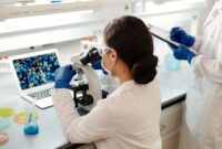 Seorang peneliti medis sedang mengamati sampel sel berbasis rekayasa genetika di dalam laboratorium canggih untuk persiapan prosedur terapi presisi pada pasien penyakit kronis.