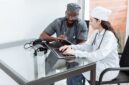 Seorang dokter sedang memberikan konsultasi medis dan penjelasan mendalam mengenai rencana pengobatan kepada pasien di ruang pemeriksaan fasilitas kesehatan.