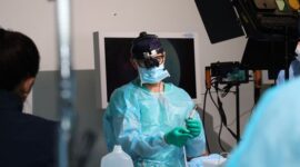 Seorang ahli bedah mengoperasikan lengan robotik presisi tinggi di ruang operasi modern untuk melakukan tindakan medis non-invasif dengan tingkat akurasi maksimal.