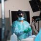 Seorang ahli bedah mengoperasikan lengan robotik presisi tinggi di ruang operasi modern untuk melakukan tindakan medis non-invasif dengan tingkat akurasi maksimal.