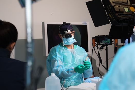 Seorang ahli bedah mengoperasikan lengan robotik presisi tinggi di ruang operasi modern untuk melakukan tindakan medis non-invasif dengan tingkat akurasi maksimal.