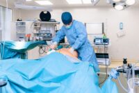 Seorang dokter bedah mengoperasikan konsol pembedahan robotik berteknologi tinggi di ruang operasi modern. Teknologi presisi ini memungkinkan tindakan medis invasif minimal dengan tingkat akurasi yang tinggi bagi keselamatan pasien.
