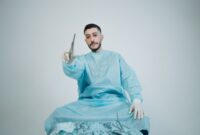 Seorang dokter spesialis mengoperasikan sistem pembedahan robotik presisi tinggi yang terhubung dengan jaringan digital untuk membantu tindakan medis berakurasi tinggi dari jarak jauh.