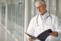 Seorang dokter ahli sedang menjelaskan hasil analisis pemetaan mikrobioma dan risiko genetik pasien menggunakan visualisasi data digital interaktif di klinik kedokteran presisi.