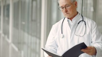 Seorang dokter ahli sedang menjelaskan hasil analisis pemetaan mikrobioma dan risiko genetik pasien menggunakan visualisasi data digital interaktif di klinik kedokteran presisi.