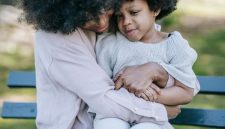 Seorang ibu memberikan dekapan hangat dan mendengarkan keluh kesah anaknya saat beraktivitas bersama di taman kota. Pendekatan pengasuhan bernuansa empati ini membantu anak mengenali serta mengelola emosi mereka secara sehat.