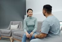 Pasangan suami istri sedang berkonsultasi secara terbuka dengan dokter spesialis untuk mendiskusikan perencanaan kesehatan reproduksi keluarga di klinik medis modern.