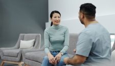 Pasangan suami istri sedang berkonsultasi secara terbuka dengan dokter spesialis untuk mendiskusikan perencanaan kesehatan reproduksi keluarga di klinik medis modern.