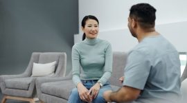 Pasangan suami istri sedang berkonsultasi secara terbuka dengan dokter spesialis untuk mendiskusikan perencanaan kesehatan reproduksi keluarga di klinik medis modern.
