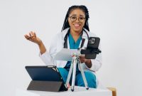 Seorang wanita berkonsultasi secara nyaman dengan dokter spesialis melalui video call di layar ponsel pintar dari ruang tamu rumahnya.