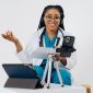Seorang wanita berkonsultasi secara nyaman dengan dokter spesialis melalui video call di layar ponsel pintar dari ruang tamu rumahnya.