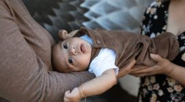 Seorang dokter spesialis anak memberikan suntikan vaksinasi dasar kepada bayi yang berada dalam dekapan hangat ibunya di klinik kesehatan.