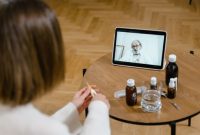 Seorang pasien sedang berkonsultasi secara virtual dengan dokter spesialis melalui layar telepon pintar untuk mendapatkan pertolongan medis awal yang praktis dari rumah.