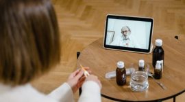 Seorang pasien sedang berkonsultasi secara virtual dengan dokter spesialis melalui layar telepon pintar untuk mendapatkan pertolongan medis awal yang praktis dari rumah.